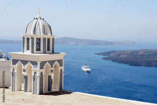 Church bell tower on Santorini Island, Greece. The view toward Caldera sea with cruise ship arriving.