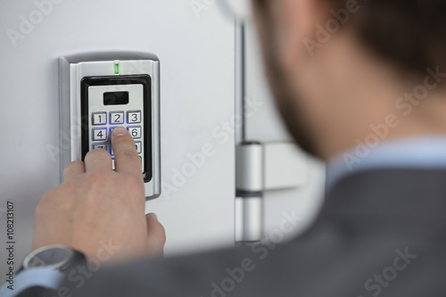 Close up of businessman hand entering security system code photo