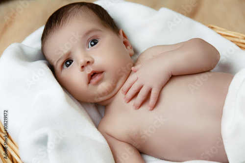 Cute shocked newborn baby lying in wicker basket