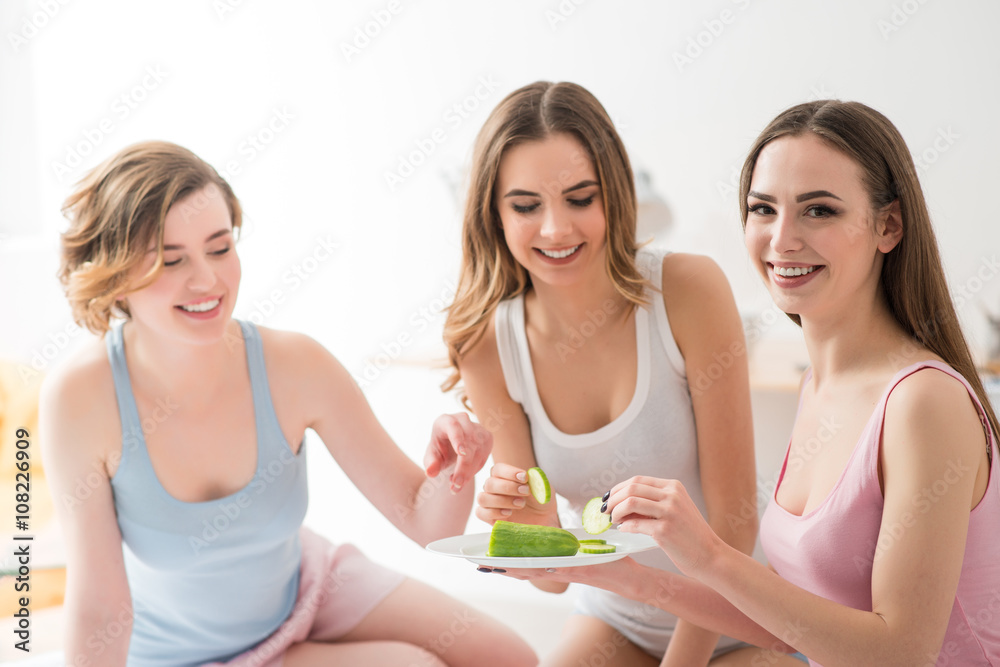 Cheerful girls eating cucumbers Cheerful girls eating cucumbers