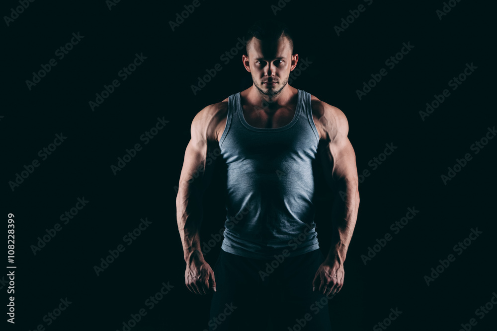 Naklejka premium Silhouette of a strong fighter. Confident young fitness man with hands and clenched fists. Dramatic light.
