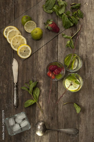Fototapeta Naklejka Na Ścianę i Meble -  cocktails with strawberry, lime and lemon and ice on an old wooden table
