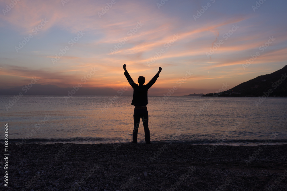 Happy free man standing on the beach at sunset Happy free man standing on the beach at sunset
