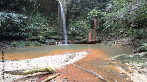 Couple swimming into a stunning multicolored natural pool with scenic waterfall in the rainforest of Lambir Hills National Park, Borneo, Malaysia. photo