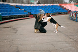 Young hipster girl with her pet estonian hound dog playing, junping and hugging and having fun outdoor at the old stadium.