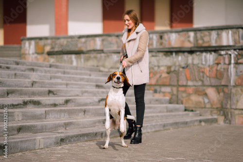 Young hipster girl with her pet estonian hound dog playing and having fun outdoor in the park.