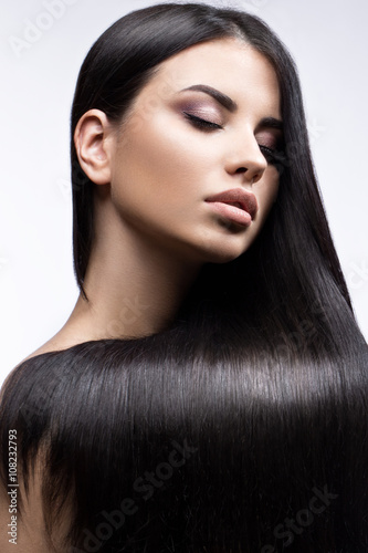 Fotografie Beautiful brunette girl in move with a perfectly smooth hair, and classic make-up