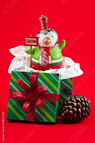 view of christmas box with penguin toy and christmas bauble.