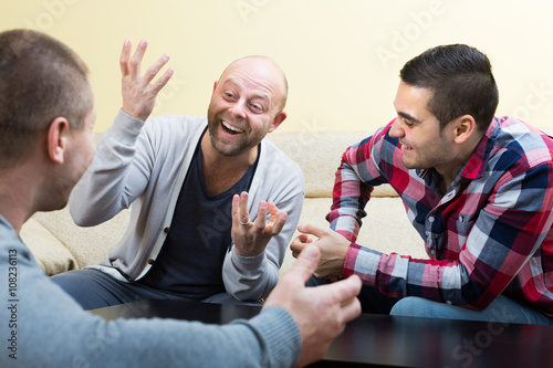 Three male friends talking at home