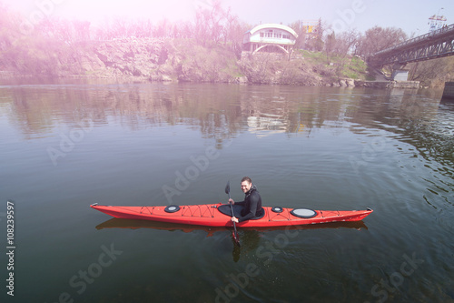 a man kayaking on a background of the city