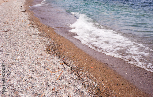 Beach of coarse sand and stones with wave.