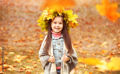 Happy young girl in yellow autumn wreath in park