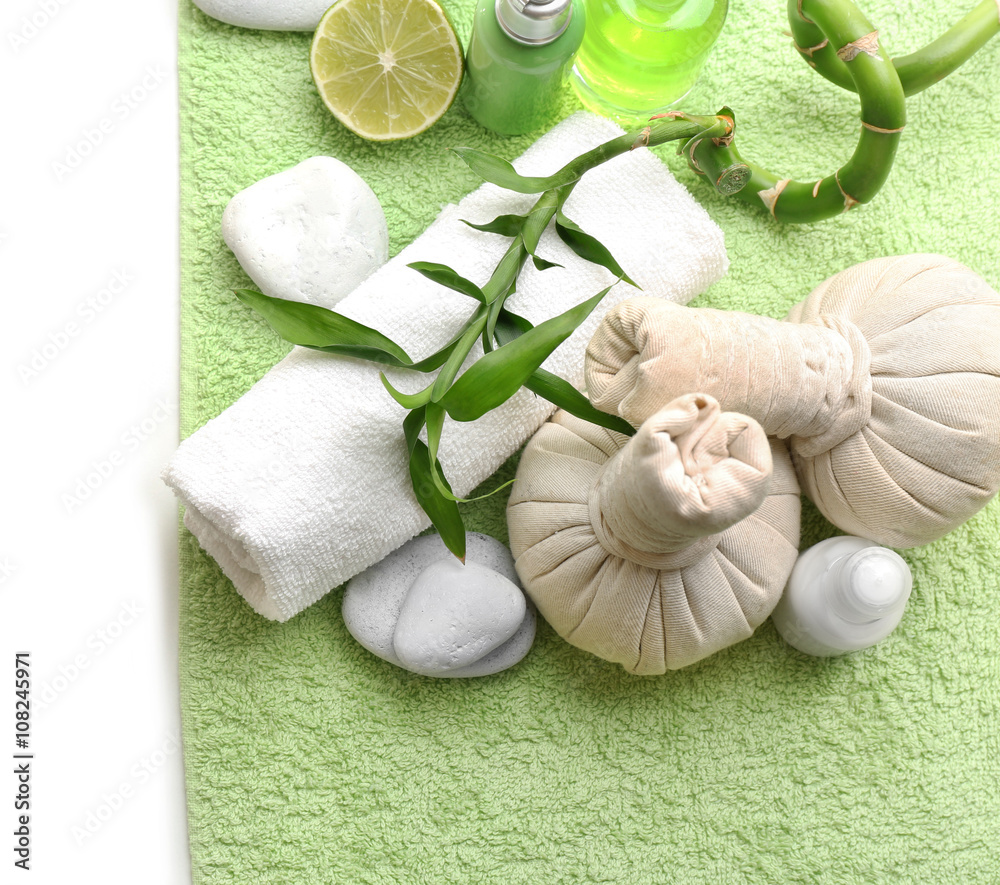 Relaxing spa set on green soft towel which lying on white background