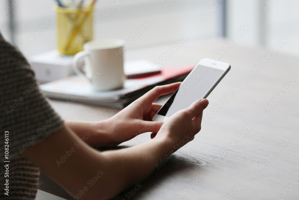 Woman's hands using mobile phone at the table