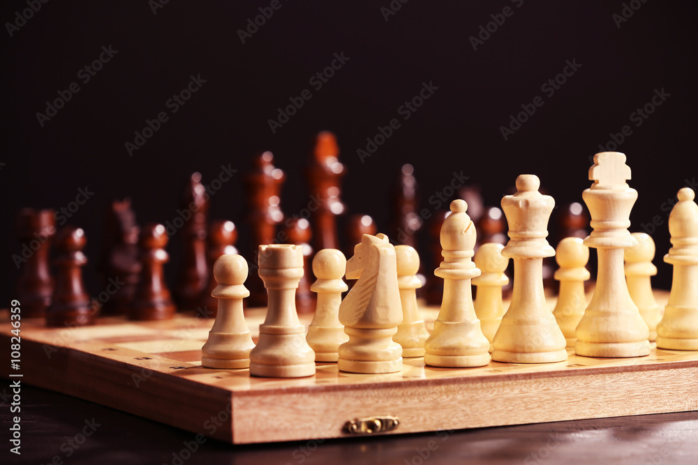 Chess pieces and game board on black background