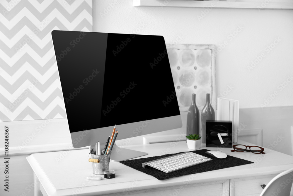 Modern wide screen monitor on white table in room interior Modern wide screen monitor on white table in room interior