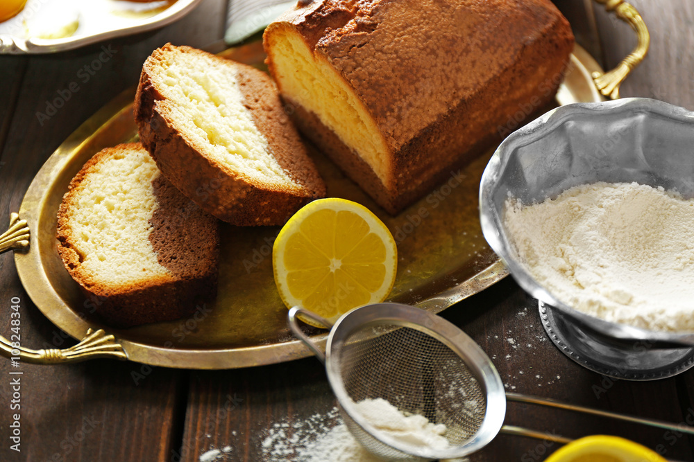 Delicious sweet cake bread in metal tray with lemons on wooden table closeup Delicious sweet cake bread in metal tray with lemons on wooden table closeup