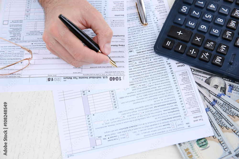 Man filling American form of Individual Income Tax Return at the table Man filling American form of Individual Income Tax Return at the table