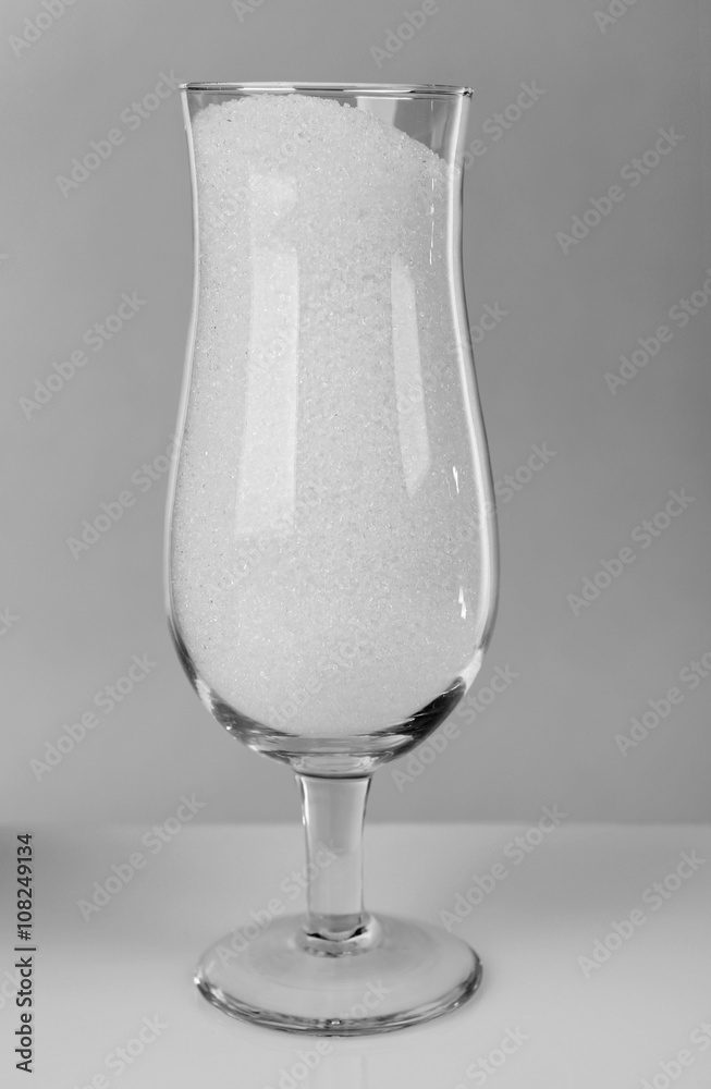 Hurricane glass filled with granulated sugar on grey background Hurricane glass filled with granulated sugar on grey background