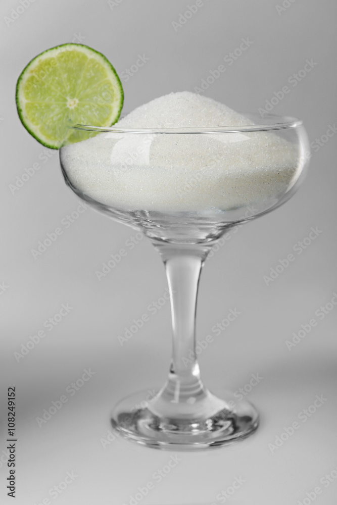Margarita glass with granulated sugar and slice of lime on grey background