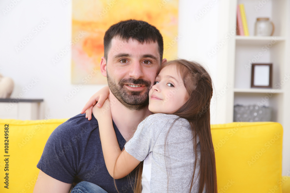 Father and  daughter sitting on the yellow sofa.