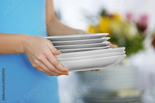 Woman holding stack of clean plates, close up © Africa Studio
