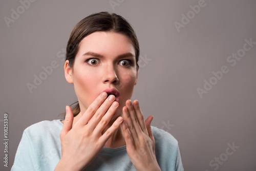Pleasant girl expressing surprise on grey background 