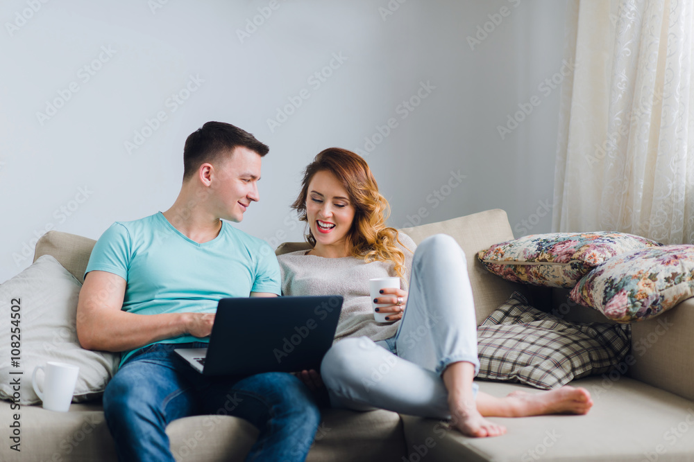 Young couple lying on couch, man using laptop computer. Young couple lying on couch, man using laptop computer.