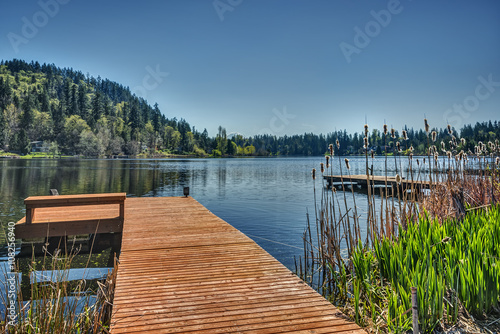 A Pier and Boat Ramp Stretch out into the Calm and Still Waters of a nondescript Pacific Northwest Lake with Mount Rainier in the Distance