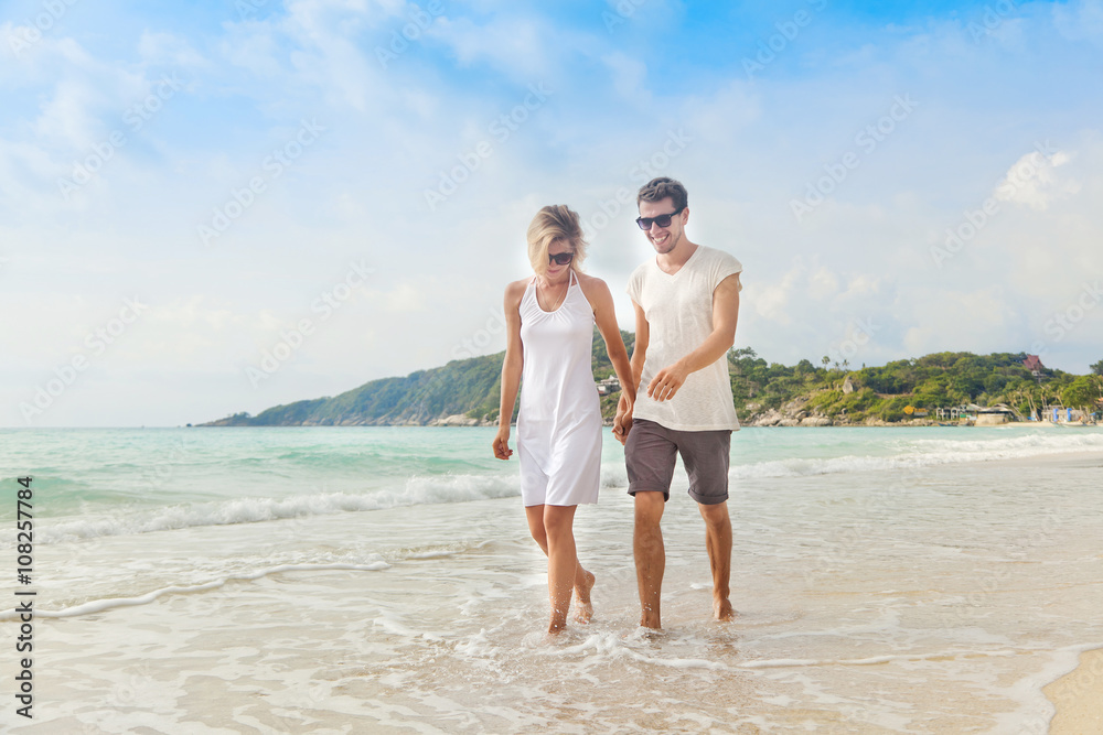 Beautiful young couple walking along the shore of a tropical sea