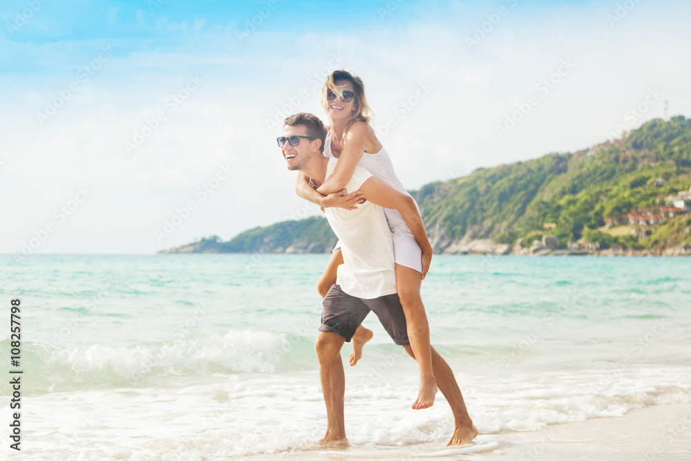 beautiful young couple walking along the shore of a tropical sea