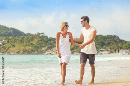 Beautiful young couple walking along the shore of a tropical sea
