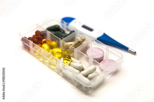 Different pills, medications, the pills in the box for drugs closeup with thermometer on white background. photo