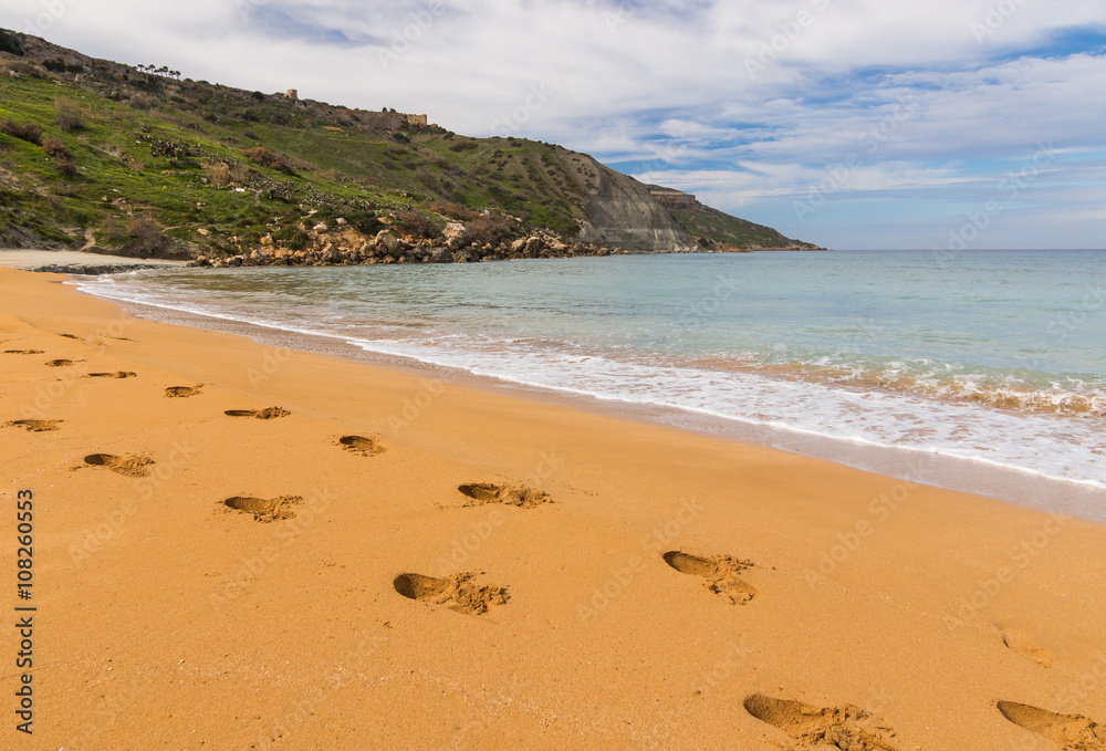 Footprints in sand at Ramla Bay, Malta island. Scenic view of orange sand at the beach and sea