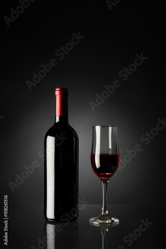 Glass of red wine and bottle on a black background