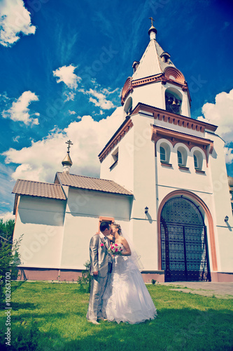 Newly married kissing on a background of the church field instag photo