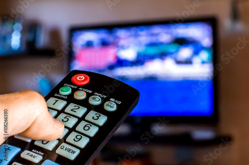 Hand hold the remote control to change channesl on Tv