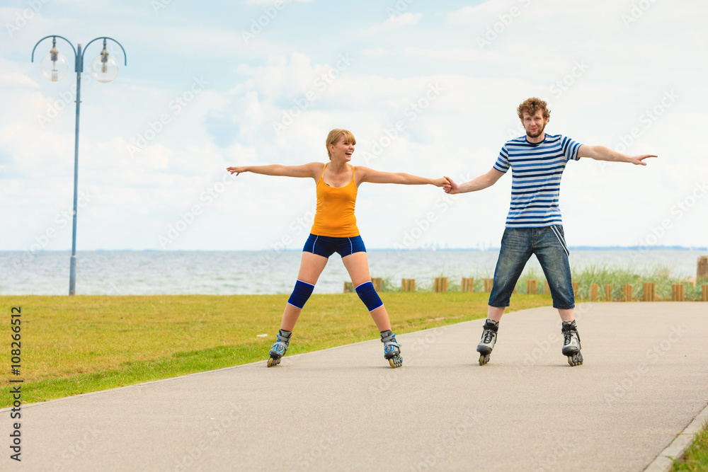Obraz premium Young couple on roller skates riding outdoors