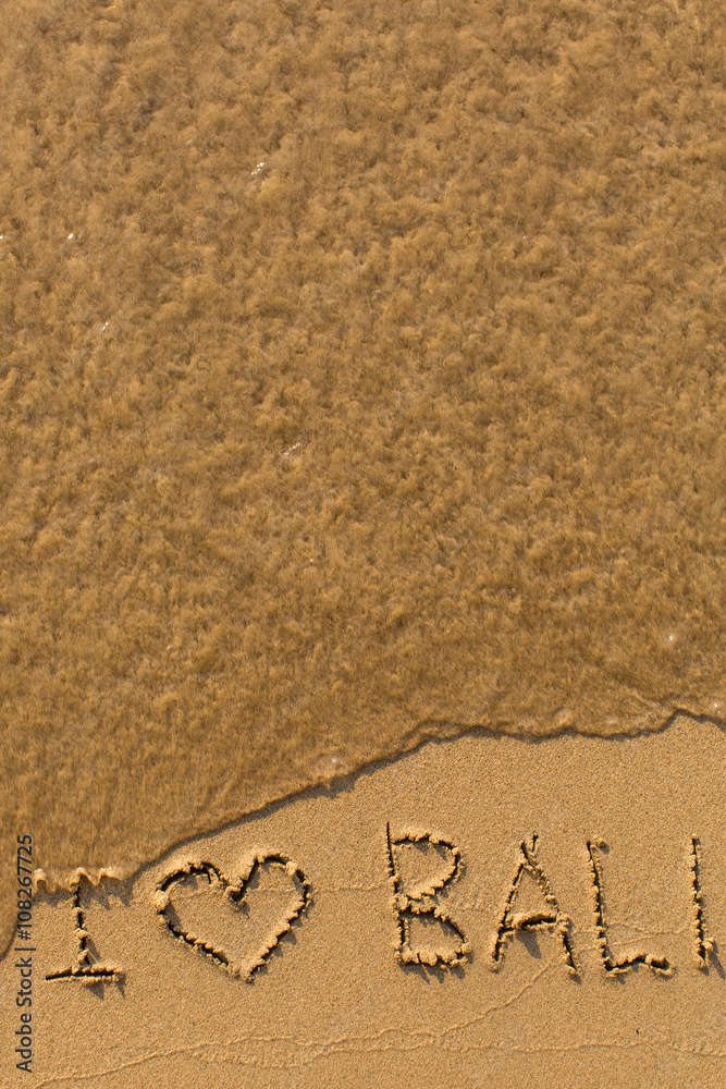 Fototapeta premium I love Bali - phrase written by hand on the beach with soft waves.