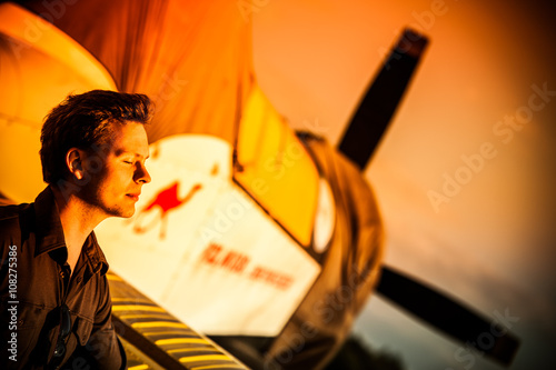 Outdoor fashion shot of male model posing with vintage old propeller plane