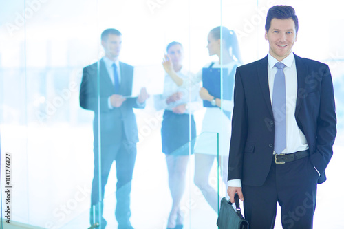 Portrait of young businessman in office with colleagues in the background © lenets_tan