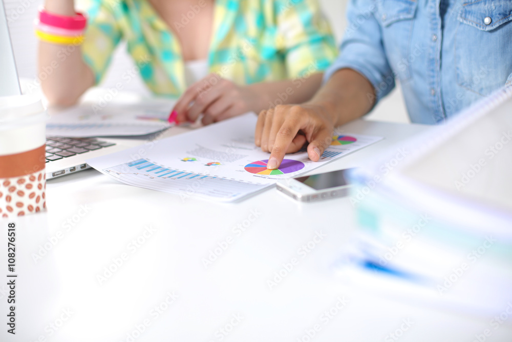 Two women working together at office, sitting on the desk Two women working together at office, sitting on the desk