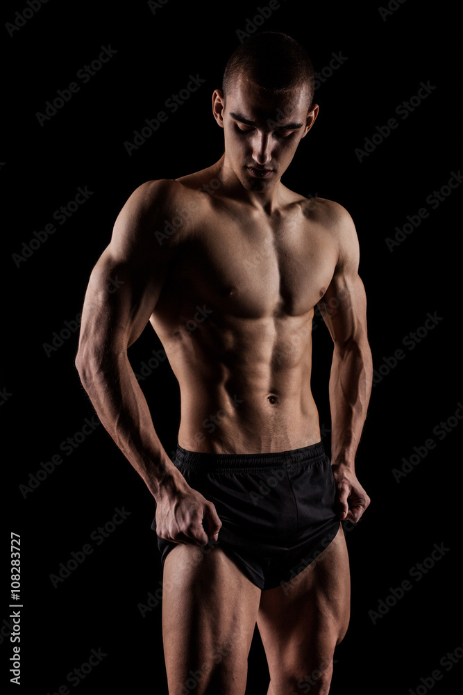 Sexy Athletic Man showing six pack abs. Isolated on black background with copyspace Sexy Athletic Man showing six pack abs. Isolated on black background with copyspace
