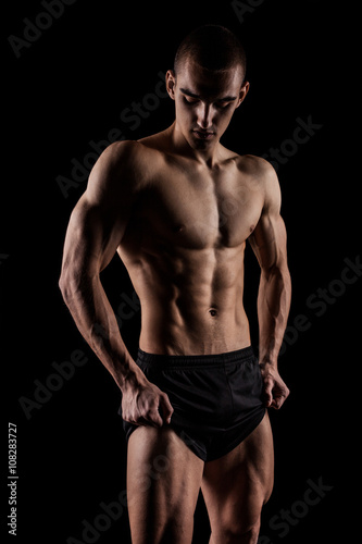Sexy Athletic Man showing six pack abs. Isolated on black background with copyspace