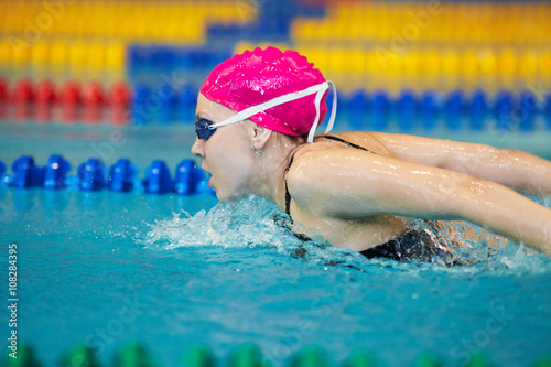 young woman swims the butterfly in the pool