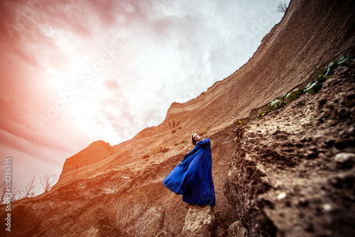 Woman in long blue dress on the sand canyon