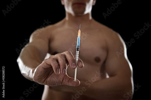 young athletic sportsman holding syringe in sport doping and cheat concept