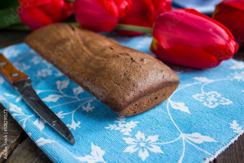 Chocolate banana bread on a blue napkin and red tulips