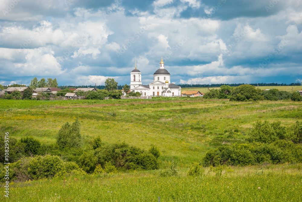 Russian summer landscape with a field and the white church