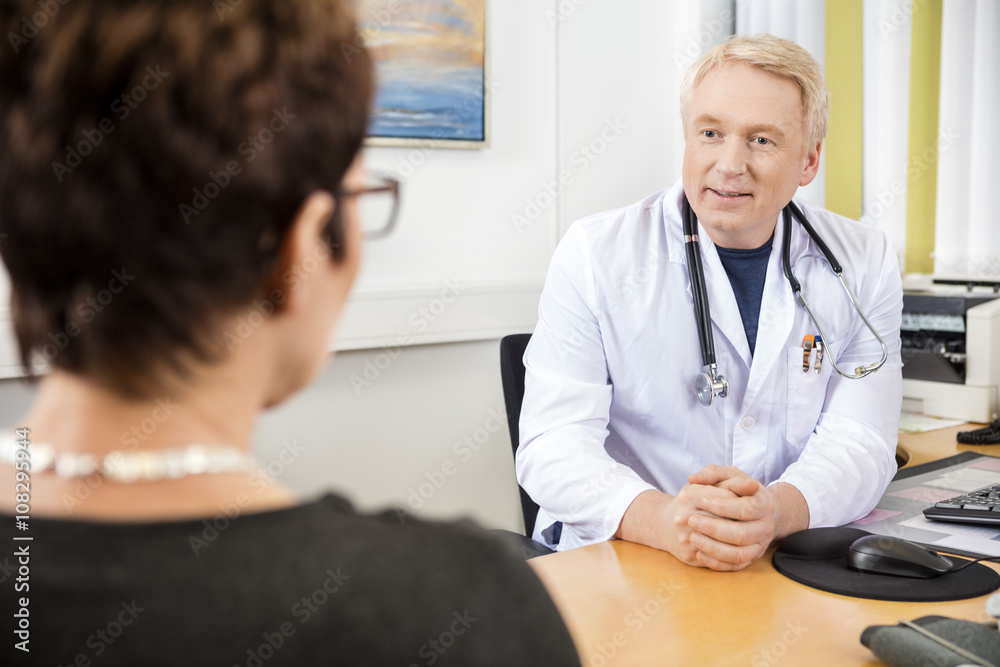 Fototapeta premium Doctor Looking At Female Patient At Desk